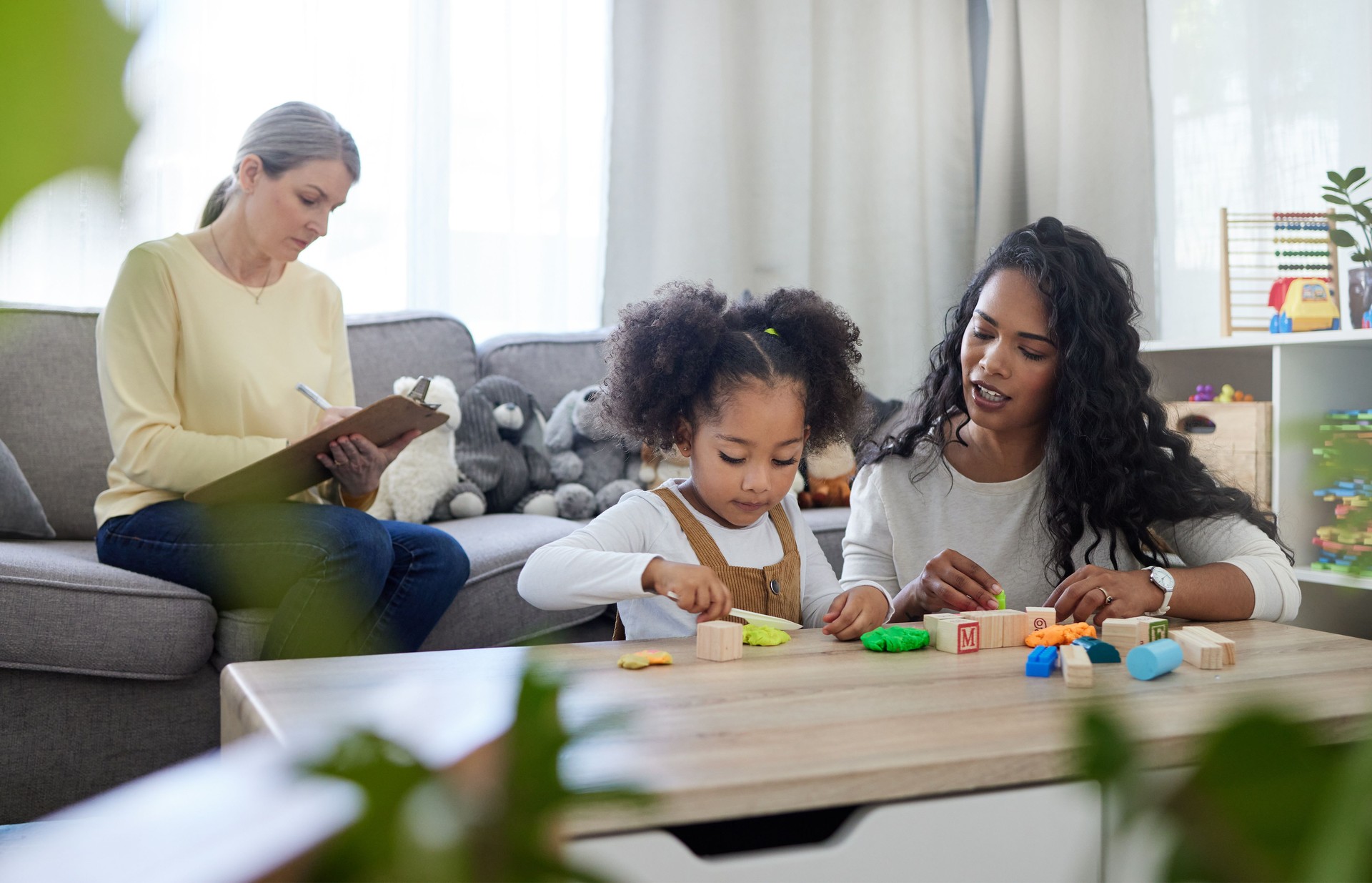 Shot of a mature therapist observing how a young mother interacts with her daughter